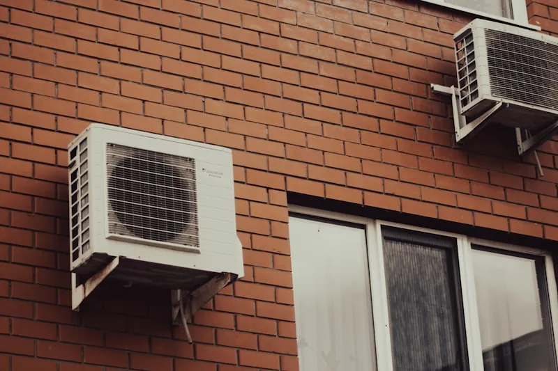 Unit outdoor AC di dinding bata yang menunjukkan tanda perlu diservice